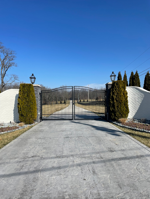 Arched black iron gate with white brick walls and lantern posts